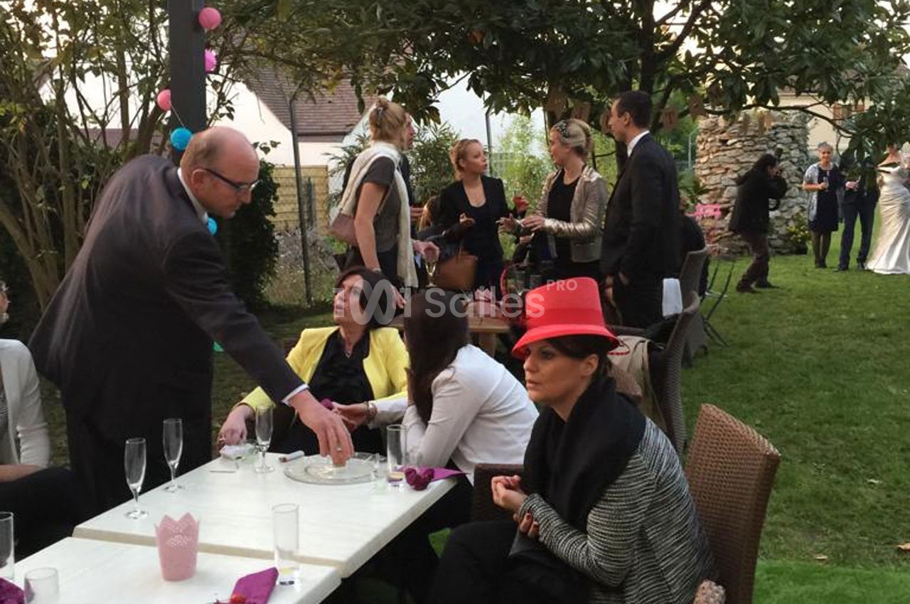 Personnes discutant et partageant un moment convivial dans un jardin lors d'un événement en plein air.