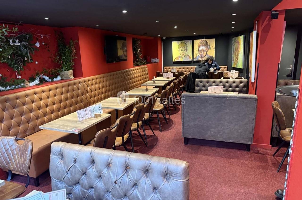 Salle de restaurant avec banquettes en cuir, tables en bois, décorations murales et ambiance chaleureuse.