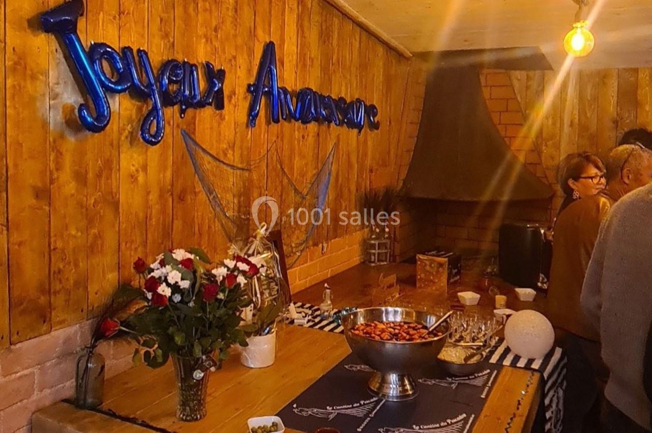 Décoration d'anniversaire avec des ballons ’Joyeux Anniversaire’, des fleurs et un buffet dans une pièce en bois.