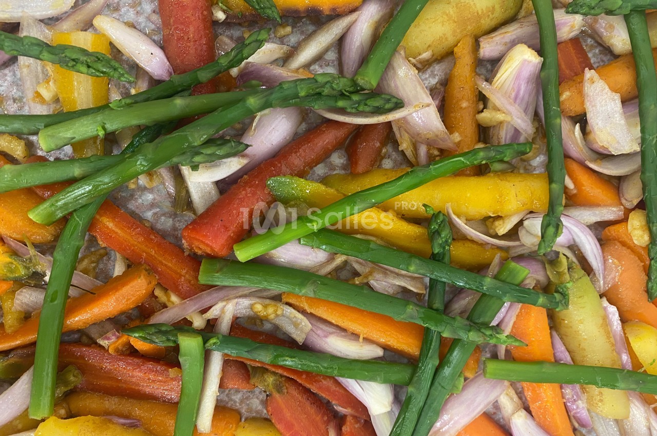 Légumes colorés, dont carottes, asperges et échalotes, disposés sur une plaque de cuisson.