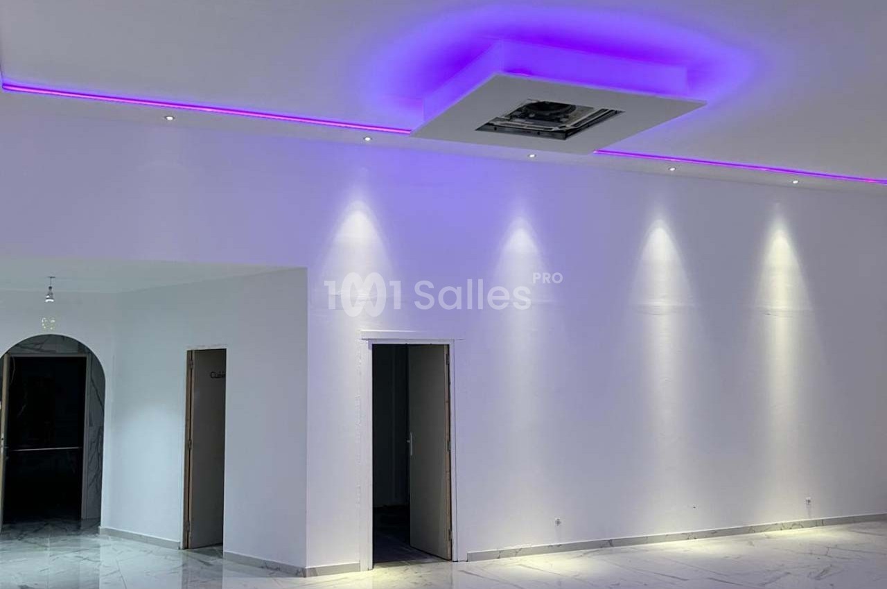 Plafond blanc avec éclairage LED violet intégré, murs blancs et sol en marbre clair dans une pièce moderne.