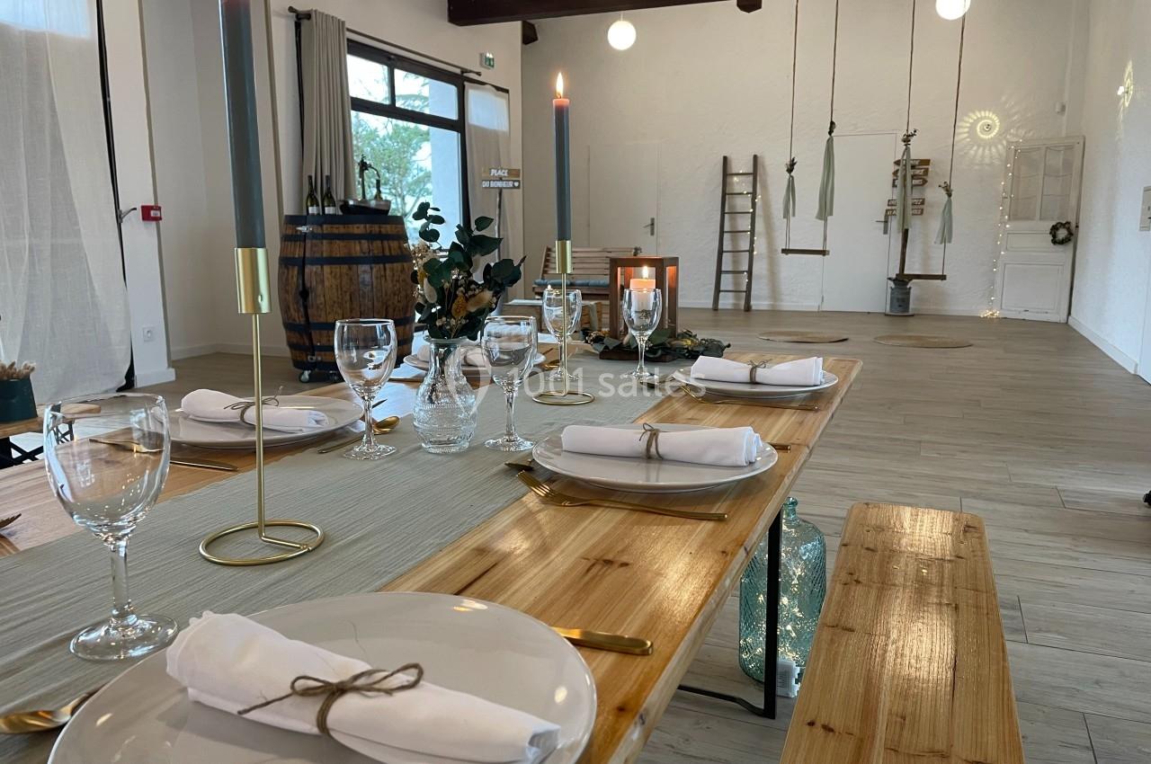 Table en bois dressée avec des assiettes, serviettes pliées, bougies et décorations dans une salle lumineuse au style…