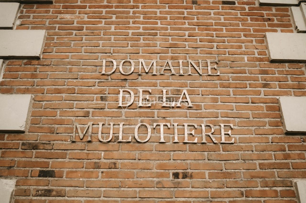 Texte ’Domaine de la Mulotière’ inscrit sur un mur en briques rouges avec des encadrements en pierre.