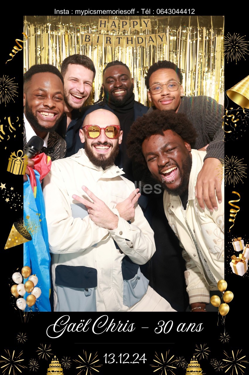 Un groupe d'hommes souriants posant devant un rideau doré lors d'une fête d'anniversaire.