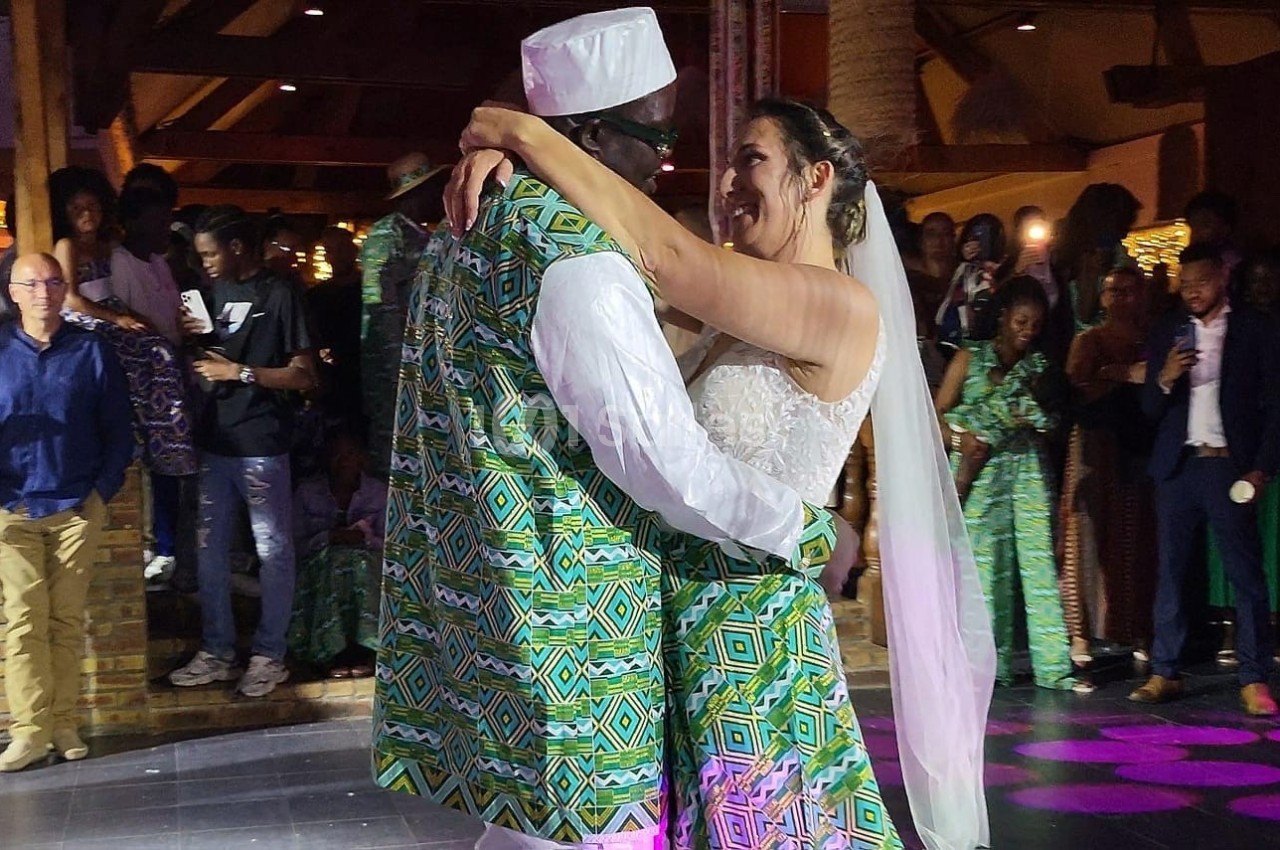 Un couple en tenue traditionnelle danse lors d'une réception de mariage, entouré d'invités.