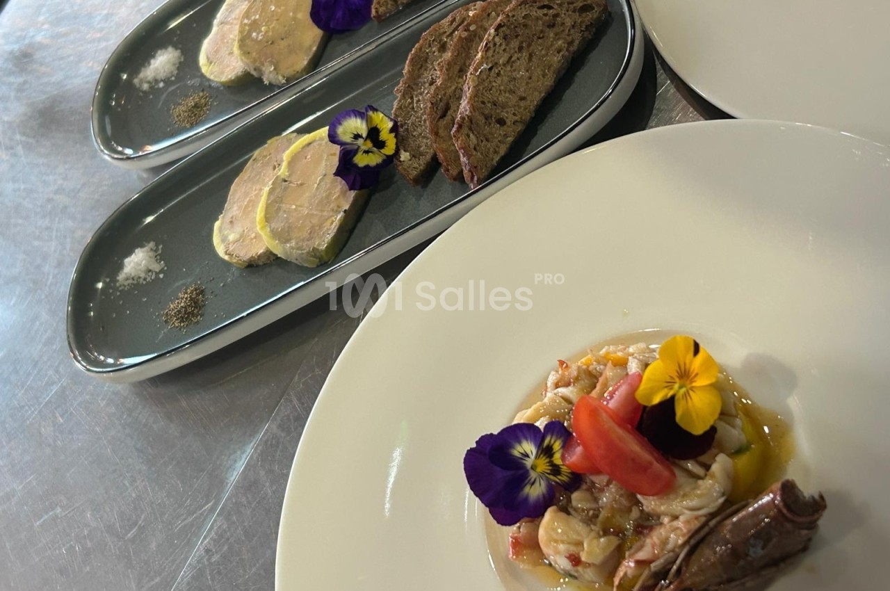 Assiette de foie gras avec pain et fleurs comestibles, accompagnée d'une salade colorée sur une autre assiette.