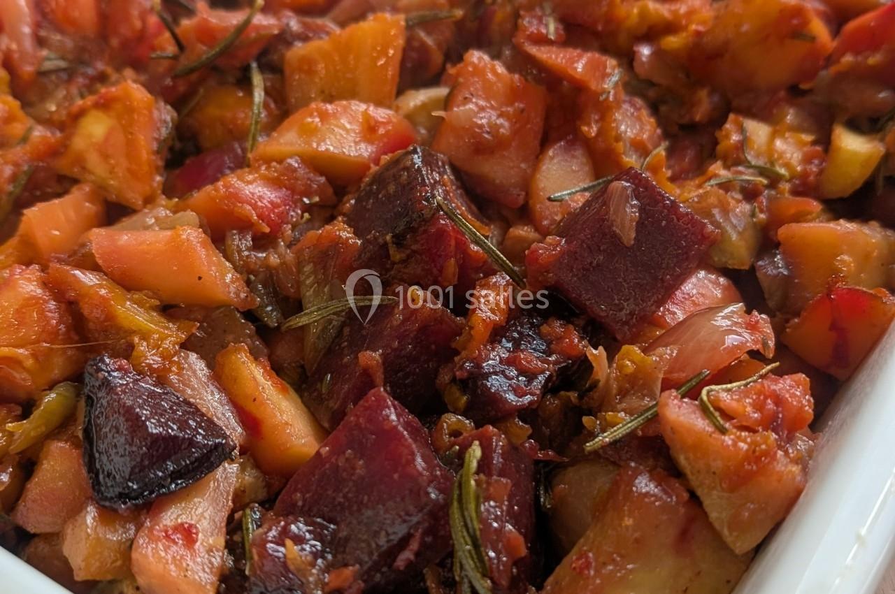 Légumes rôtis en morceaux, incluant betteraves, pommes de terre et carottes, assaisonnés d'herbes et de sauce tomate.