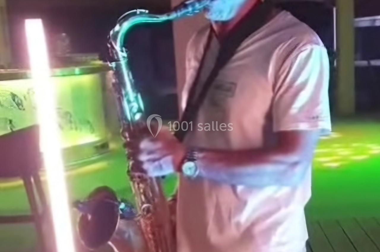 Un musicien joue du saxophone sur une scène éclairée par des lumières colorées.