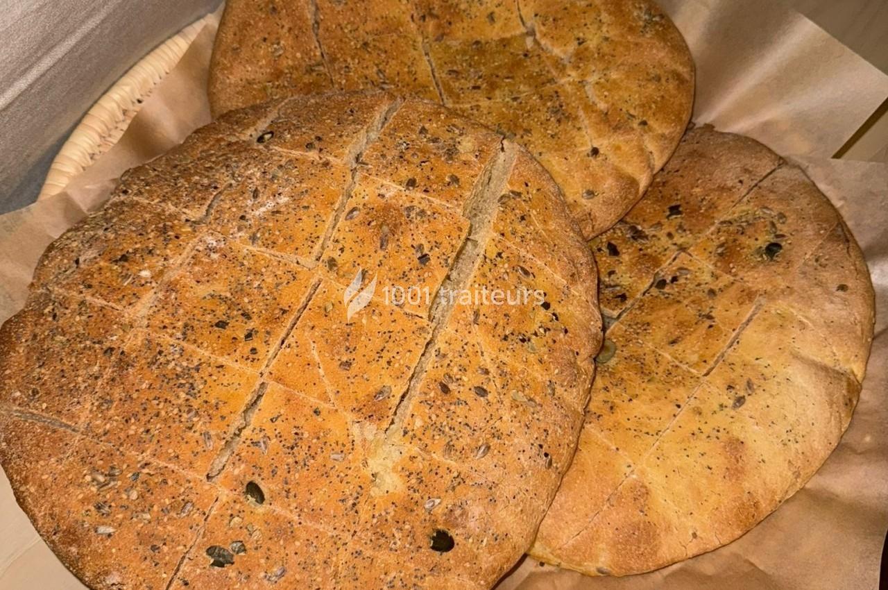 Pains ronds dorés avec une texture grillée, disposés dans un panier recouvert de papier.