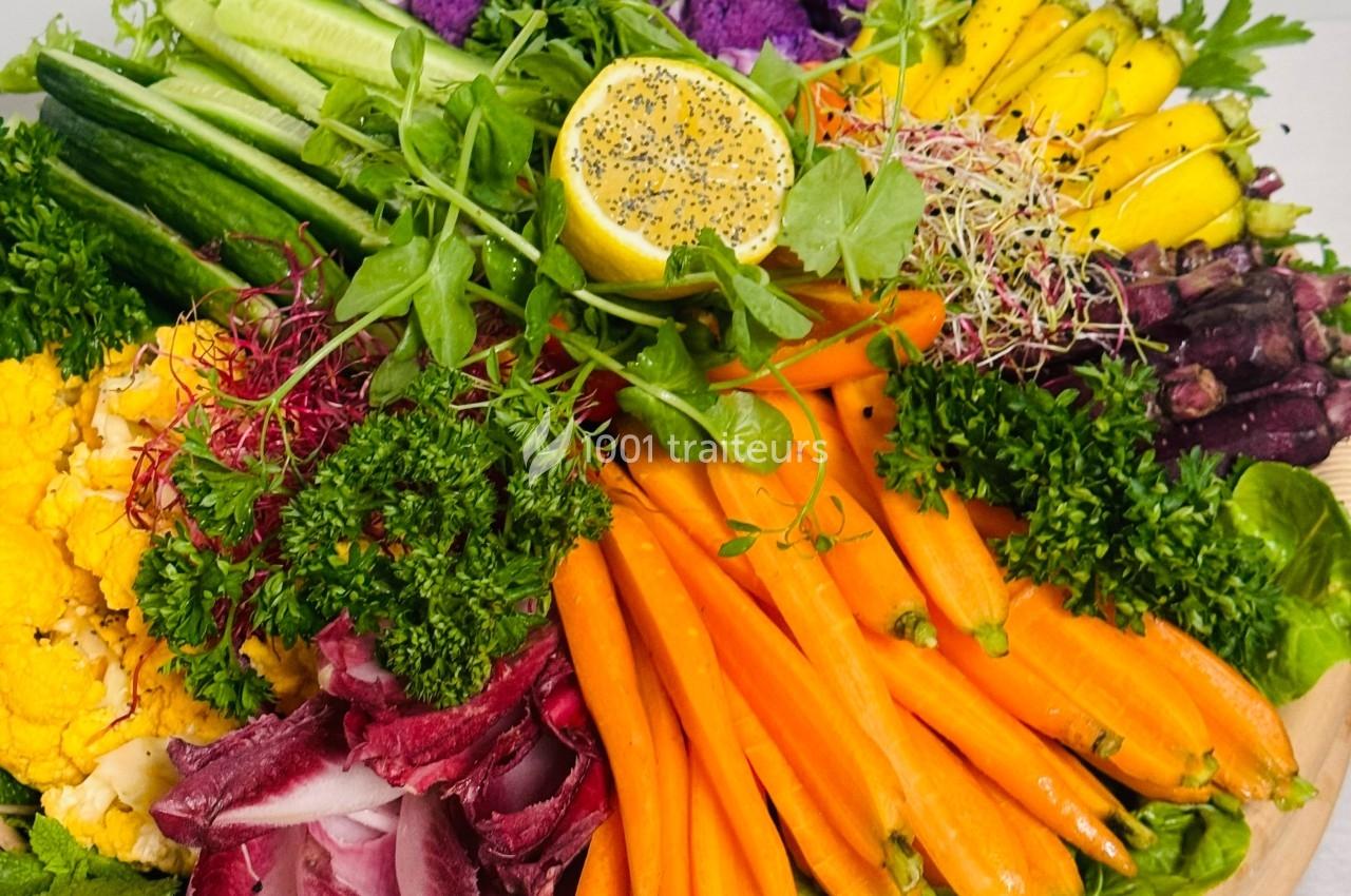 Plateau coloré de légumes frais comprenant carottes, concombres, choux-fleurs, herbes, citron et pousses.