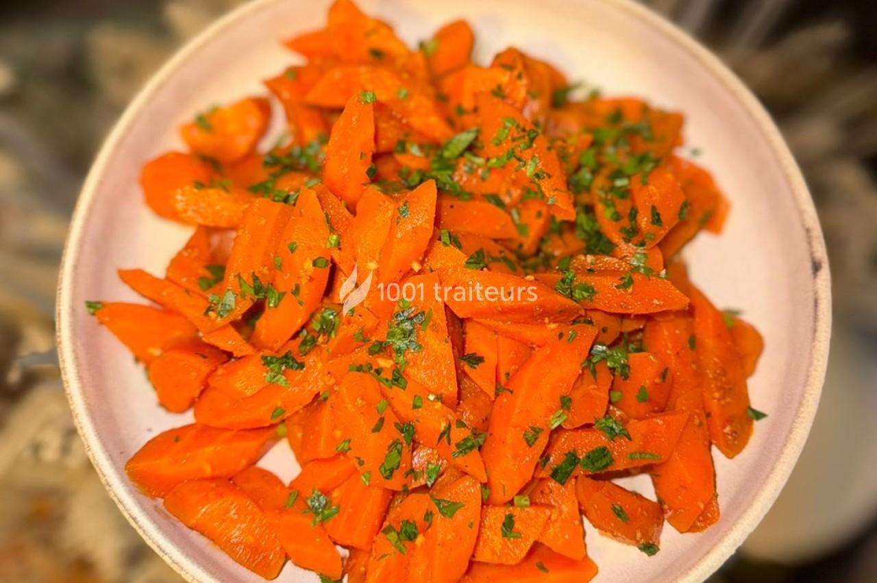 Assiette de carottes coupées en rondelles, assaisonnées et garnies de persil haché.