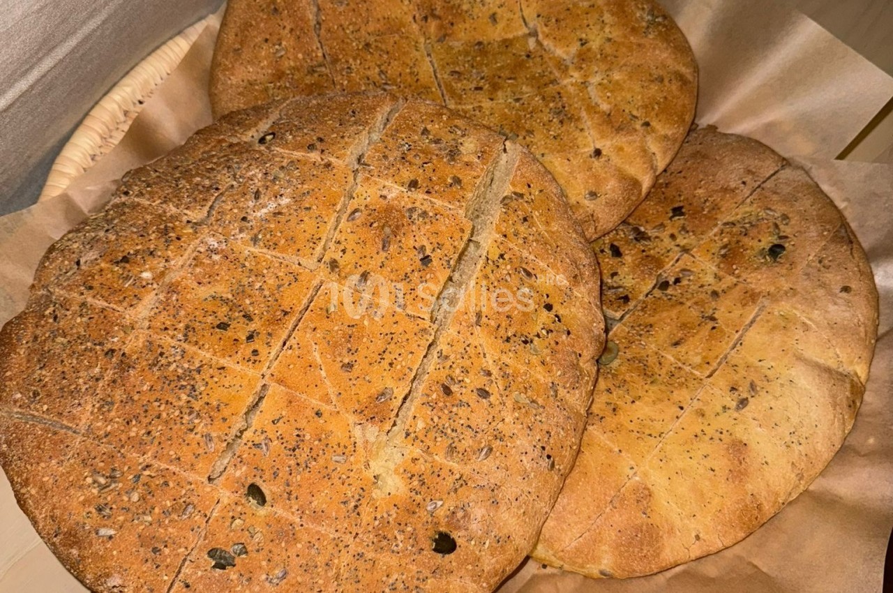 Pains ronds dorés avec une texture grillée, disposés dans un panier recouvert de papier.