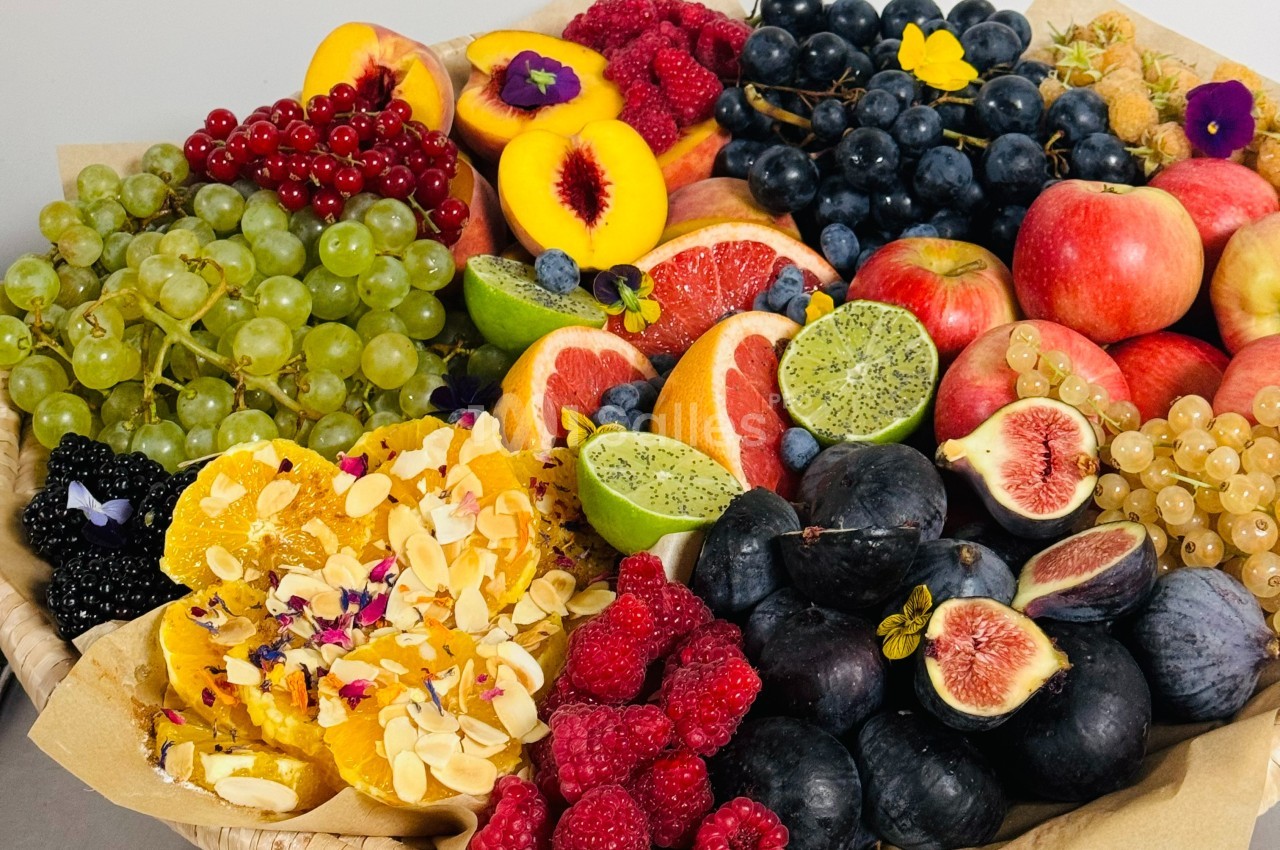 Assortiment de fruits frais variés, incluant raisins, figues, agrumes, pommes, pêches, kiwis et baies, disposés dans un…