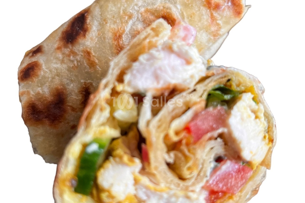 Wrap garni de légumes frais, morceaux de poulet, crevettes et sauce, présenté en coupe sur fond blanc.