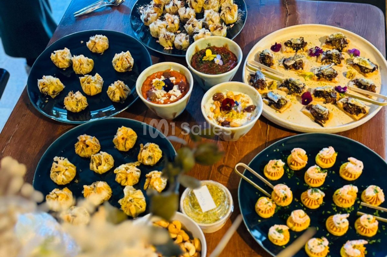 Plats variés de bouchées salées et sucrées présentés sur des assiettes et bols sur une table en bois.