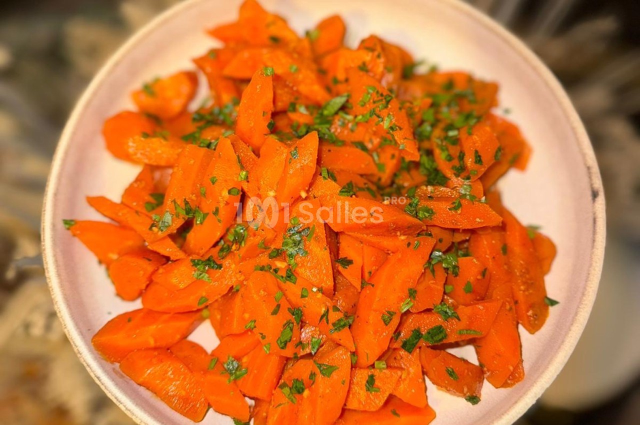Assiette de carottes coupées en rondelles, assaisonnées et garnies de persil haché.