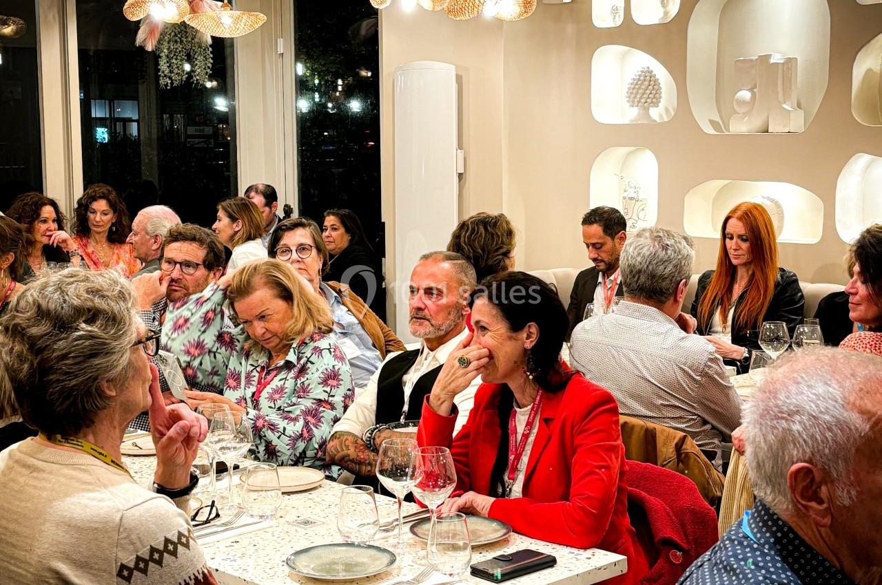 Des personnes dînent et discutent dans un restaurant lumineux à la décoration moderne et chaleureuse.