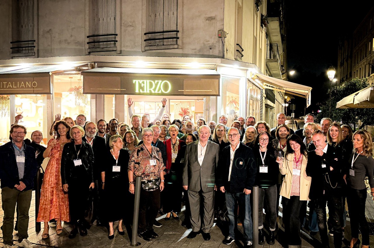 Groupe de personnes posant devant un restaurant éclairé la nuit, dans une rue urbaine.