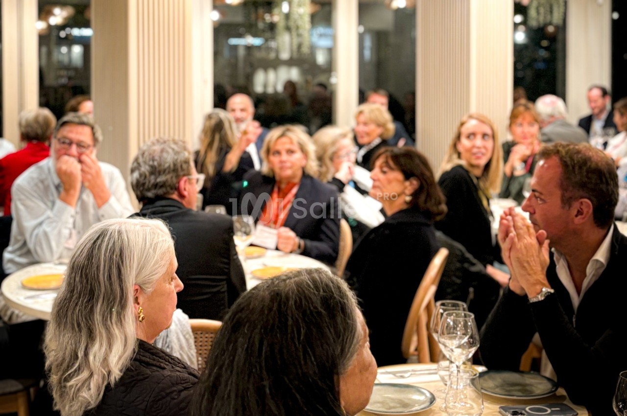 Des personnes assises autour de tables dans une salle éclairée, participant à un événement ou un dîner.