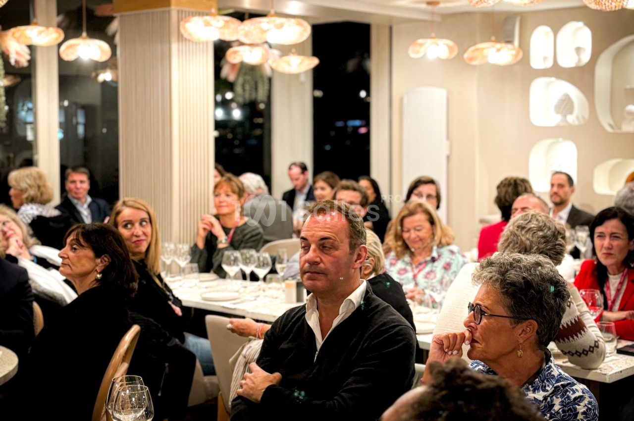 Groupe de personnes assises dans un restaurant, attentives à une présentation ou un discours.