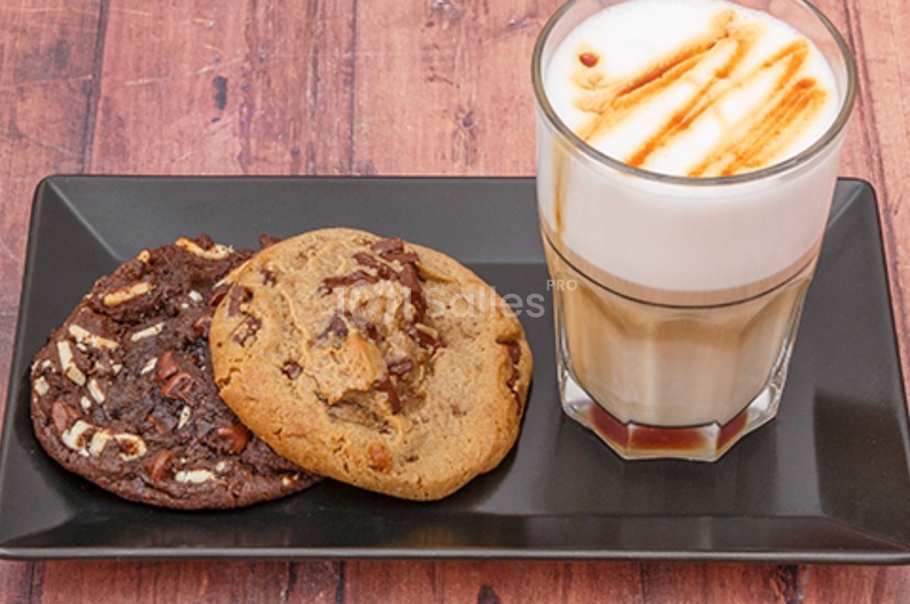 Un latte avec caramel accompagné de deux cookies, l'un au chocolat noir et l'autre aux pépites de chocolat.