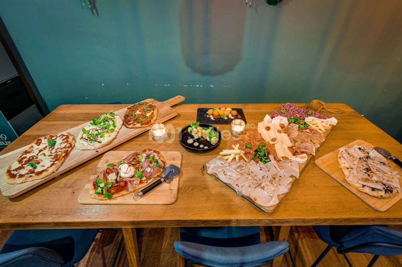 Table en bois garnie de planches de charcuterie, fromages, pains et plats variés, avec bougies décoratives.