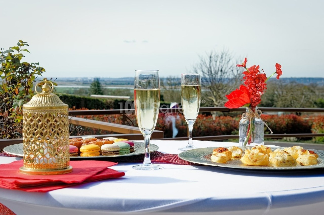 Table dressée en extérieur avec coupes de champagne, macarons, amuse-bouches et décoration florale.