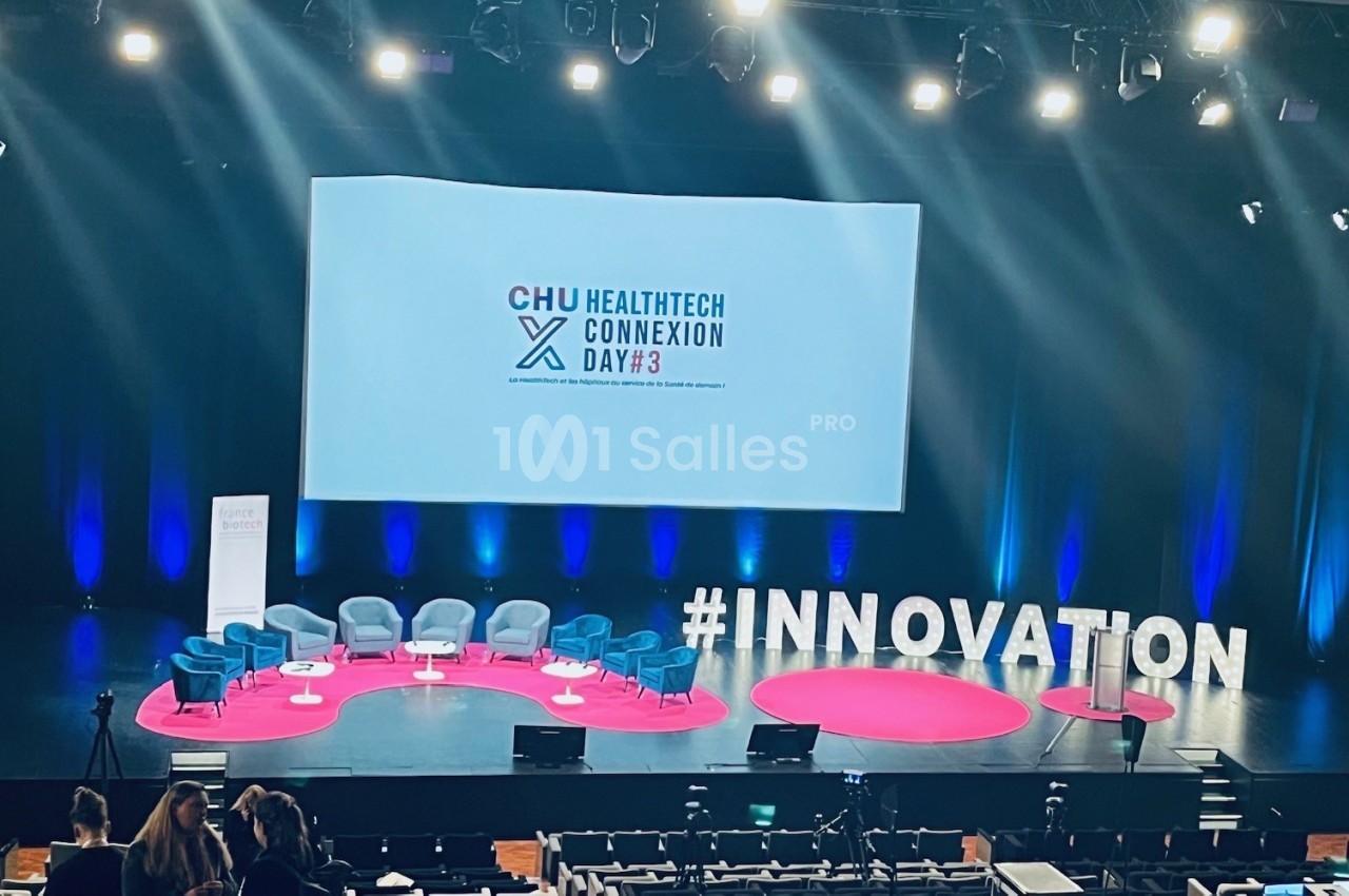 Scène d'un événement avec des sièges vides, un écran affichant ’HealthTech Connexion Day’ et le mot ’#INNOVATION’.