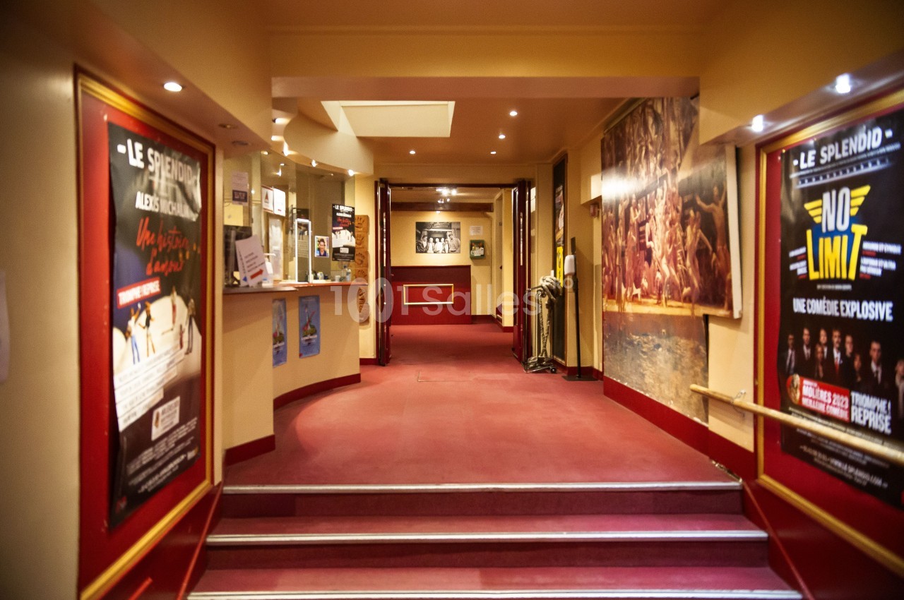 Hall d'entrée d'un théâtre avec affiches de spectacles sur les murs et comptoir d'accueil à gauche.