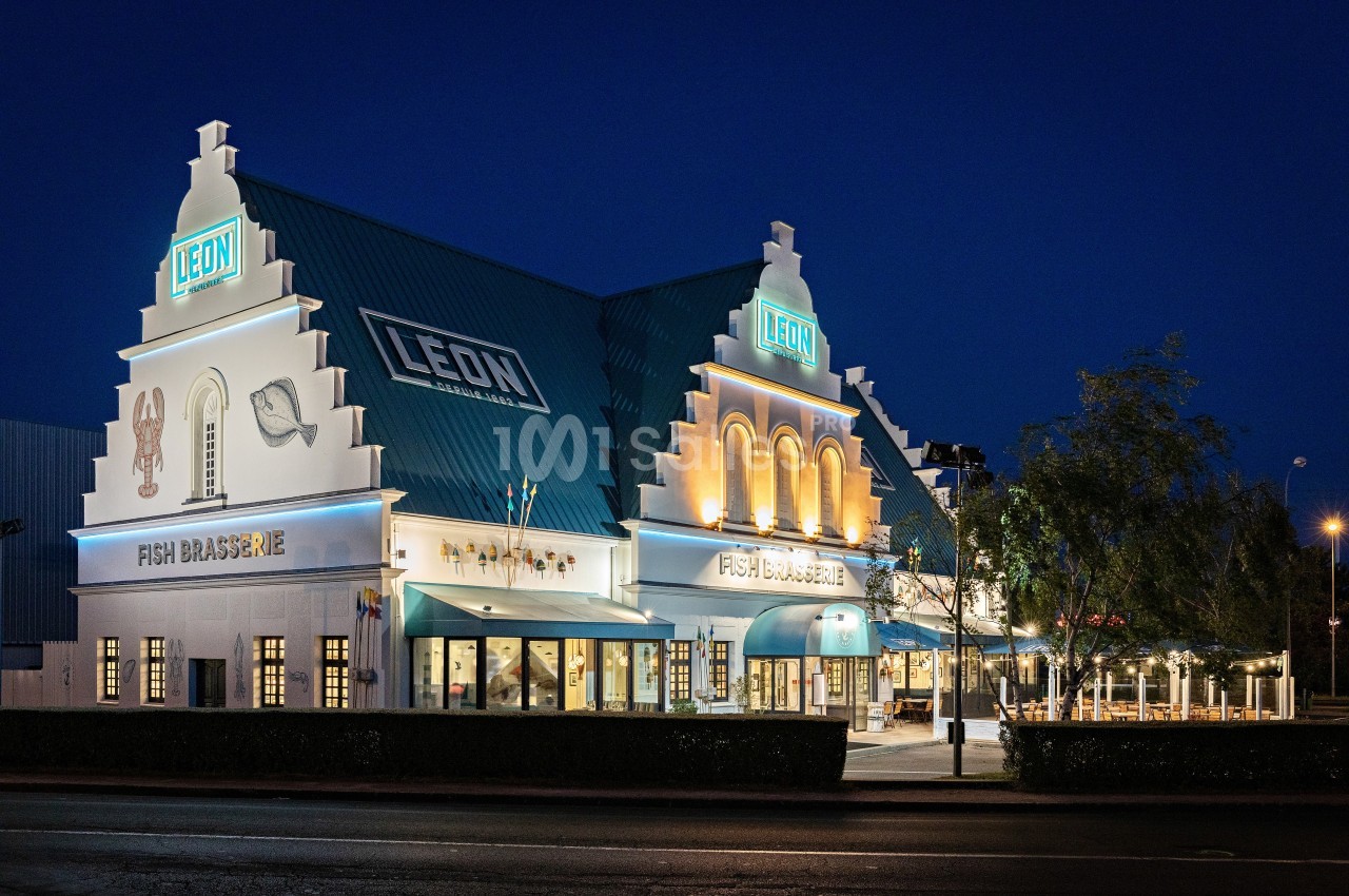 Façade éclairée d'un restaurant au style architectural nordique, avec enseignes lumineuses visibles de nuit.