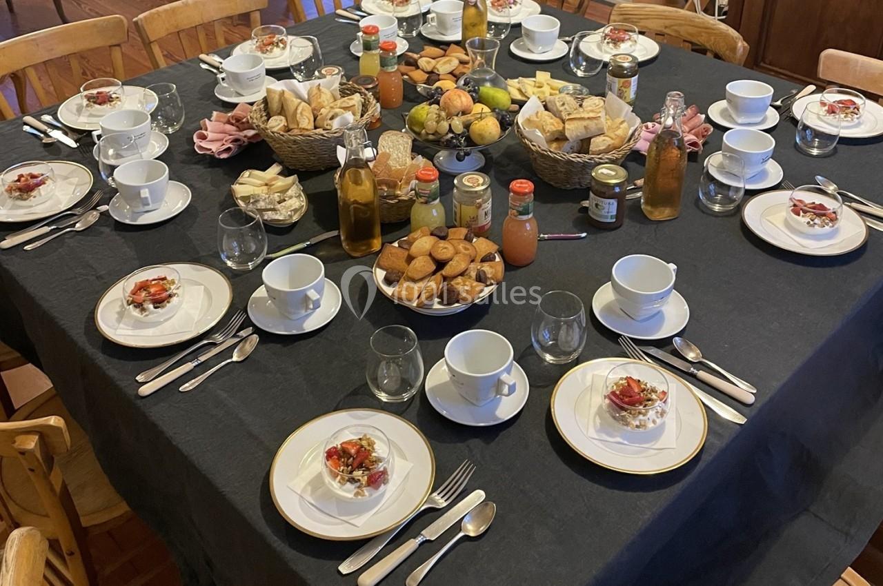 Table dressée pour un petit-déjeuner ou brunch avec viennoiseries, fruits, boissons et verrines sur une nappe noire.