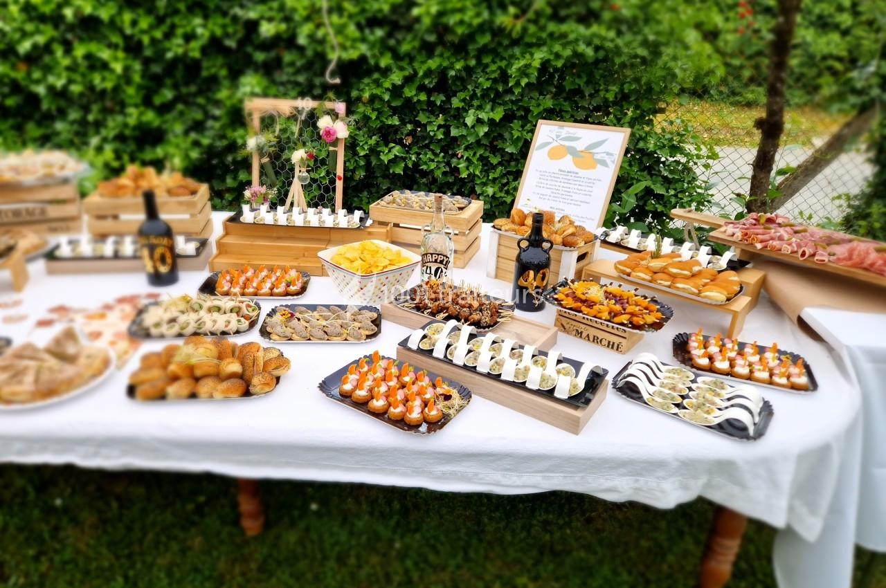 Buffet en plein air avec une variété de plats et amuse-bouches disposés sur une table blanche.