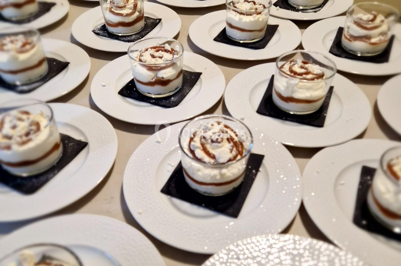 Desserts individuels en verrines avec crème et caramel, présentés sur des assiettes blanches avec des sous-verres noirs.