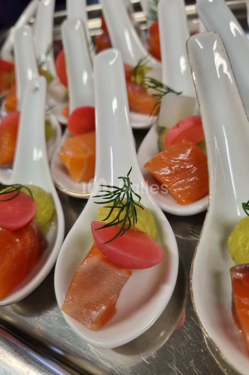 Cuillères apéritives garnies de saumon, purée verte, radis rose et brin d'aneth, présentées sur un plateau.