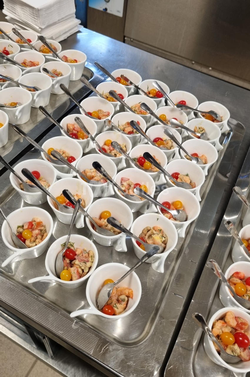 Petites verrines contenant des crevettes, tomates cerises et autres ingrédients, disposées sur un plateau en inox.