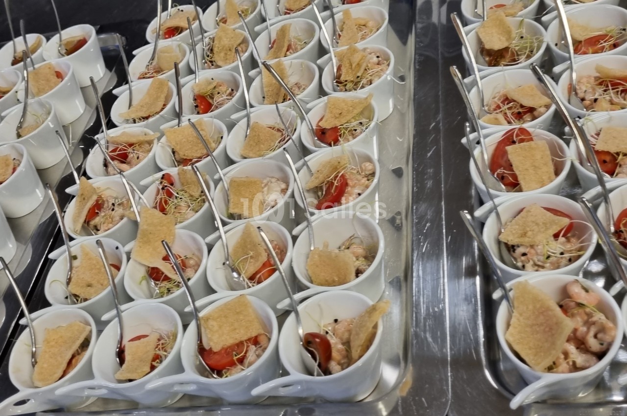 Plateaux de verrines individuelles contenant des ingrédients variés comme tomates, germes et biscuits salés.
