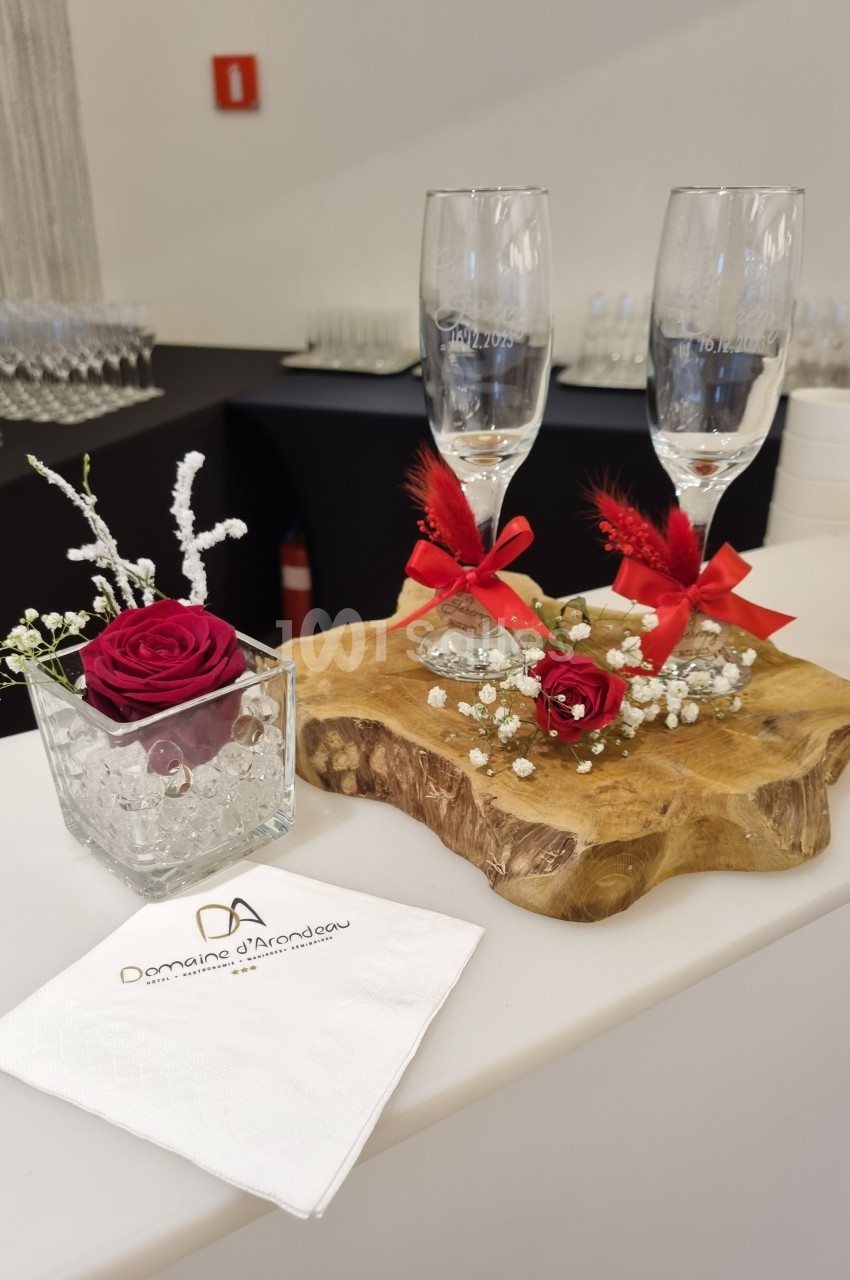 Deux flûtes décorées sur une planche en bois, avec roses rouges, gypsophile et serviette personnalisée.