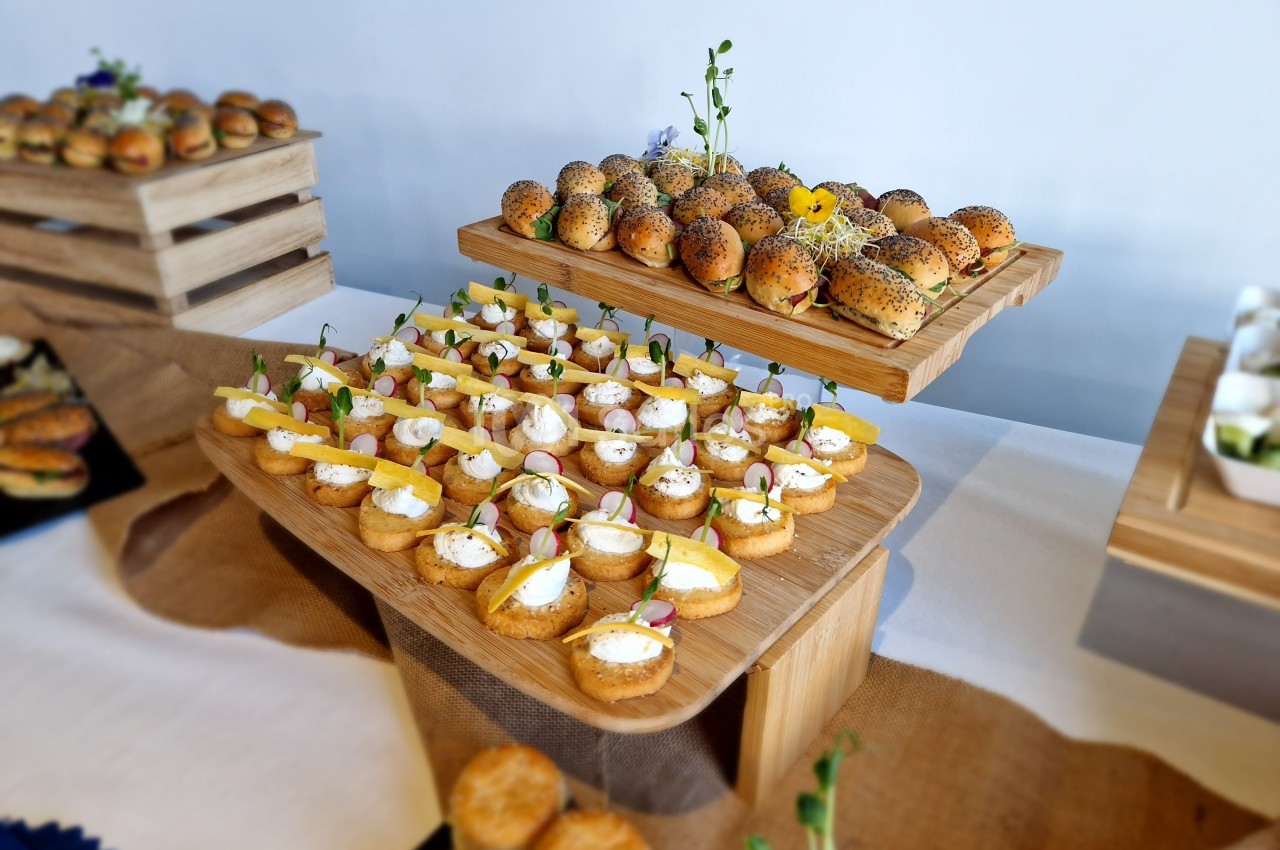 Plateaux de bouchées salées variées, incluant des mini-sandwichs et des tartines garnies, présentés sur des supports en bois.