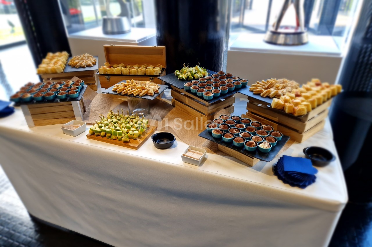 Buffet de verrines et amuse-bouches variés disposés sur des présentoirs en bois dans un cadre lumineux.
