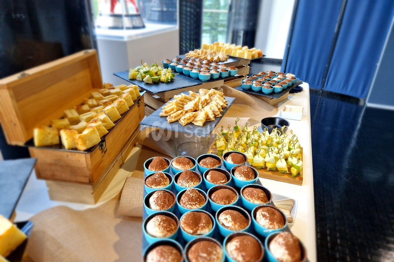 Buffet composé de desserts, verrines, sandwichs et brochettes de fruits, présenté sur des plateaux variés.