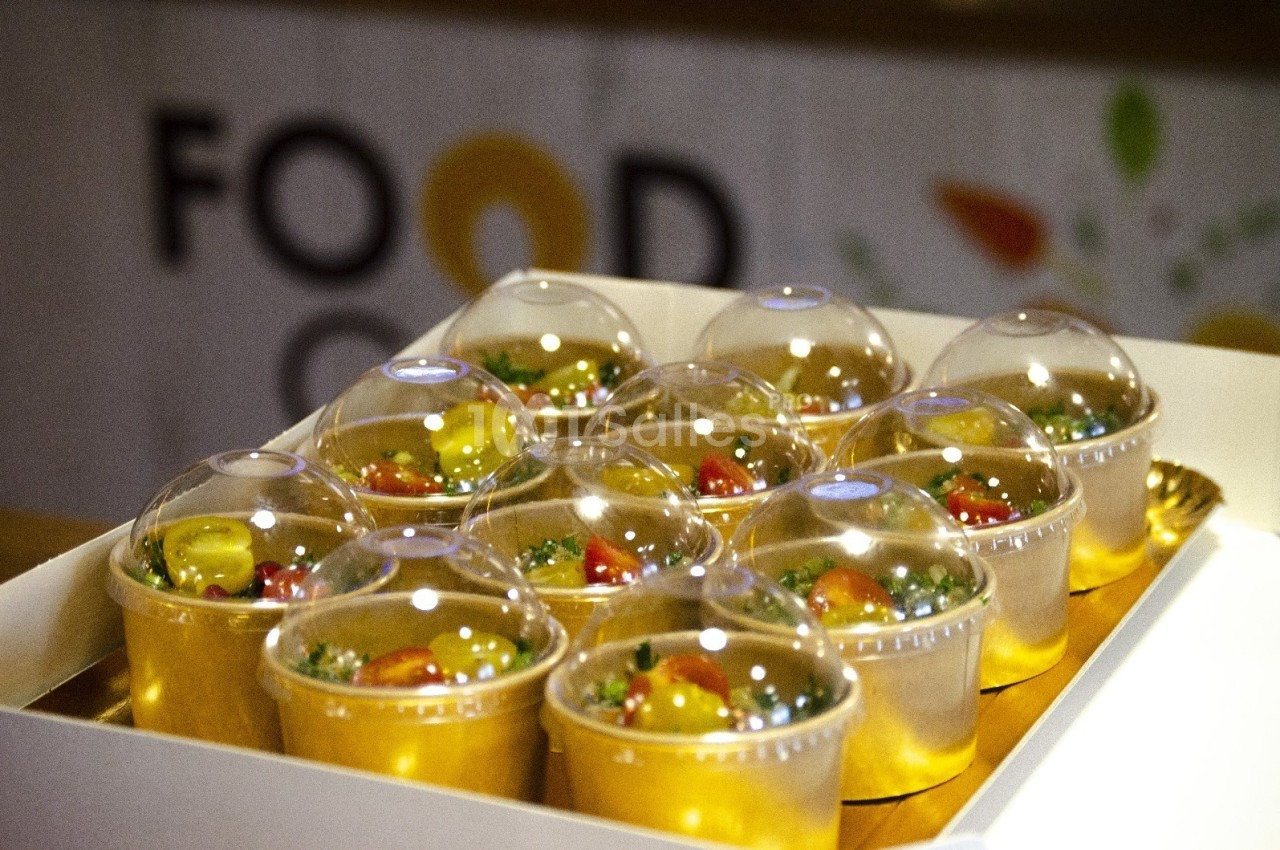 Des verrines remplies de salade colorée, recouvertes de couvercles transparents, disposées dans un plateau blanc.