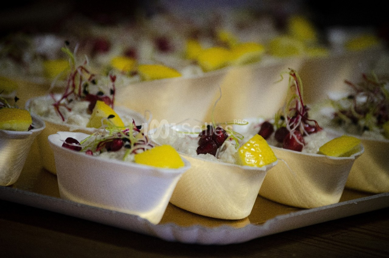 Coupes individuelles garnies de mousse blanche, morceaux de mangue, graines rouges et pousses décoratives.