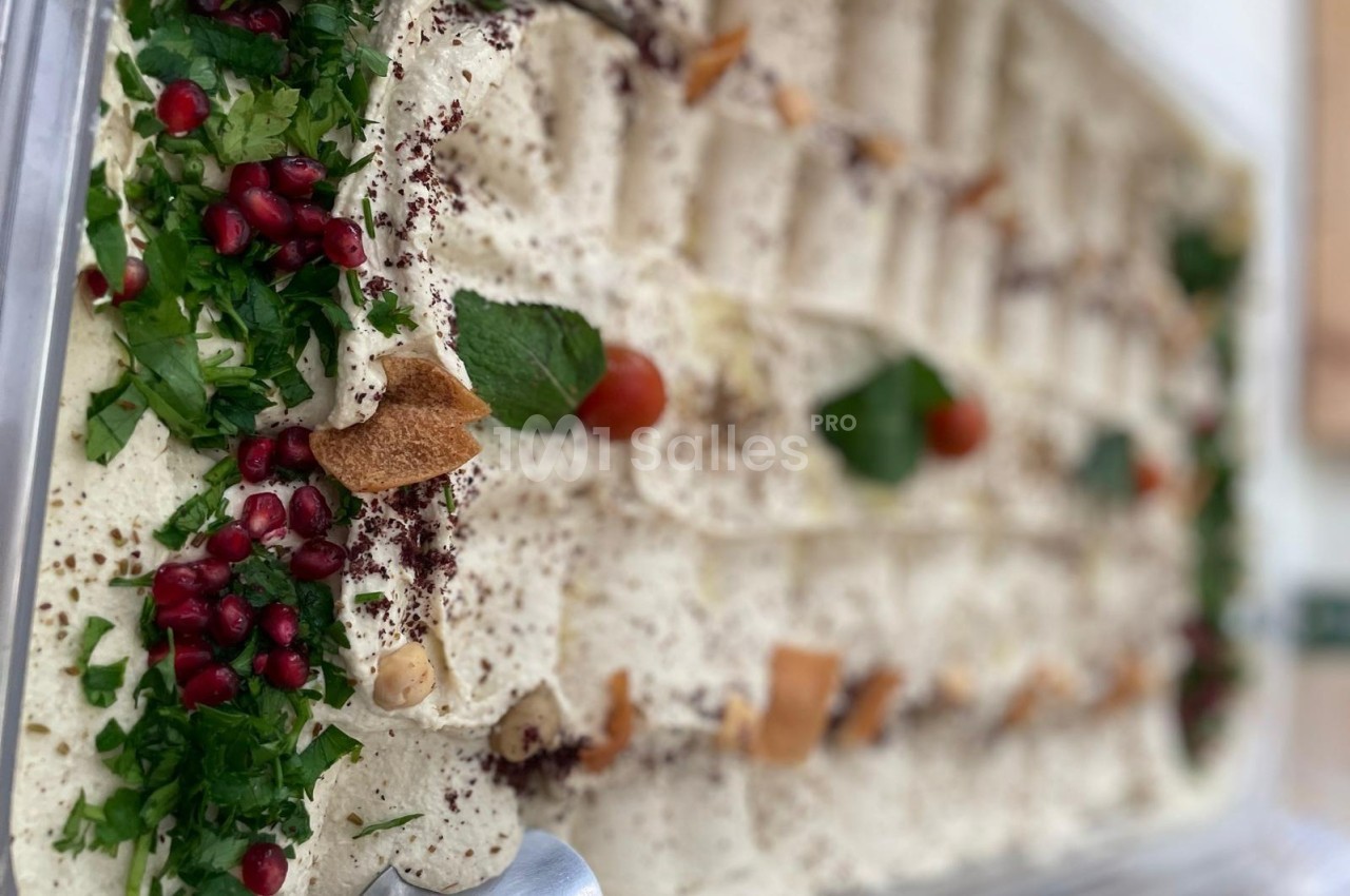 Plateau de houmous garni de persil, grenade, tomates cerises, feuilles de menthe et morceaux de pain pita.
