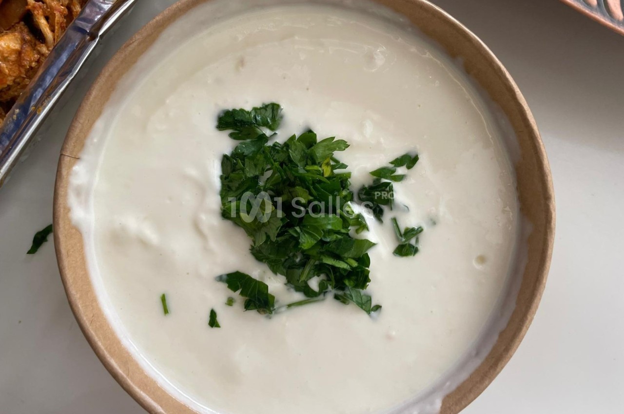 Bol de sauce blanche crémeuse garnie de feuilles de persil frais hachées.