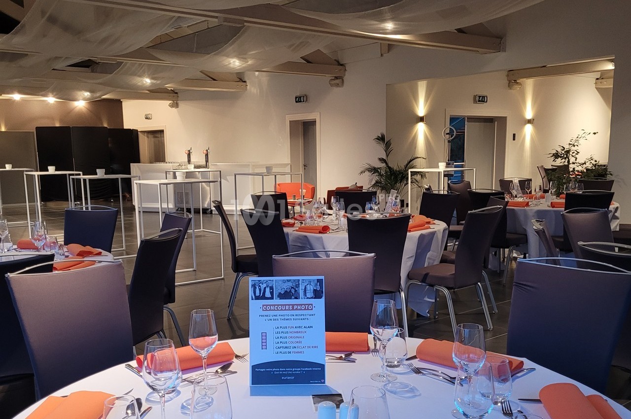 Salle de réception élégamment aménagée avec tables dressées, chaises violettes et décoration moderne.