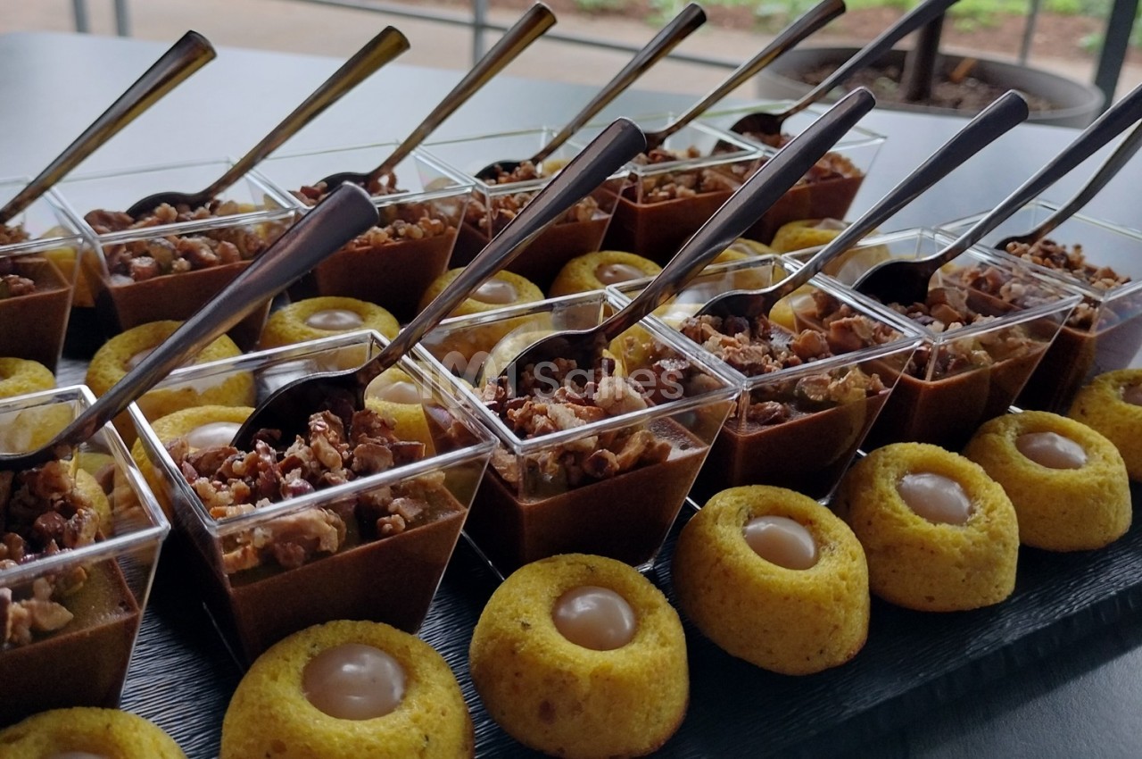 Desserts variés présentés sur un plateau, incluant des verrines au chocolat et des bouchées garnies de crème.