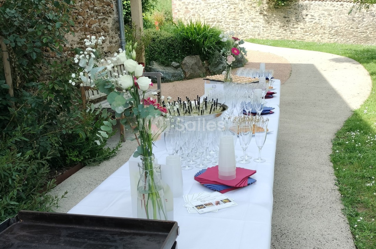 Table dressée en extérieur avec des verres à champagne, des fleurs et des serviettes colorées sur une nappe blanche.