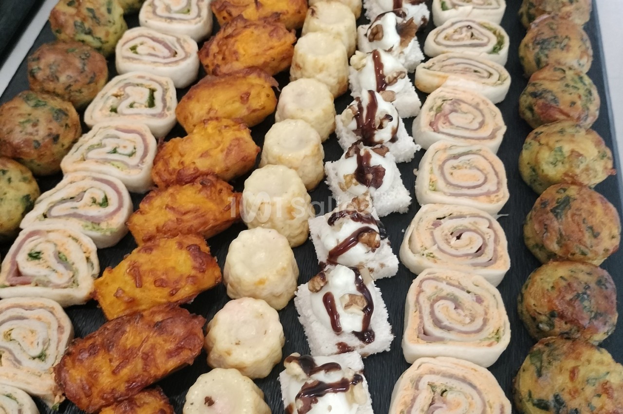 Plateau de bouchées apéritives variées : roulés, feuilletés, fromages garnis et boulettes aux herbes.
