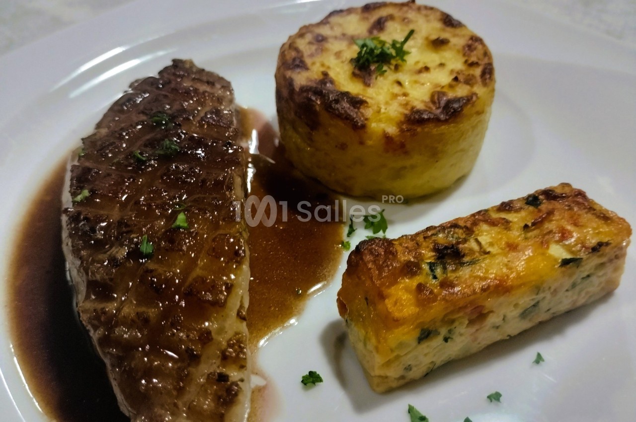 Assiette composée d'un magret de canard sauce brune, d'un gratin rond et d'un flan de légumes, décorée de persil.