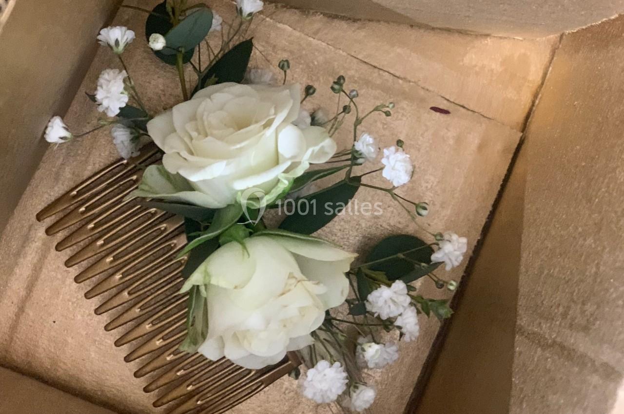 Peigne doré orné de fleurs blanches et de feuillage, présenté dans une boîte en carton.